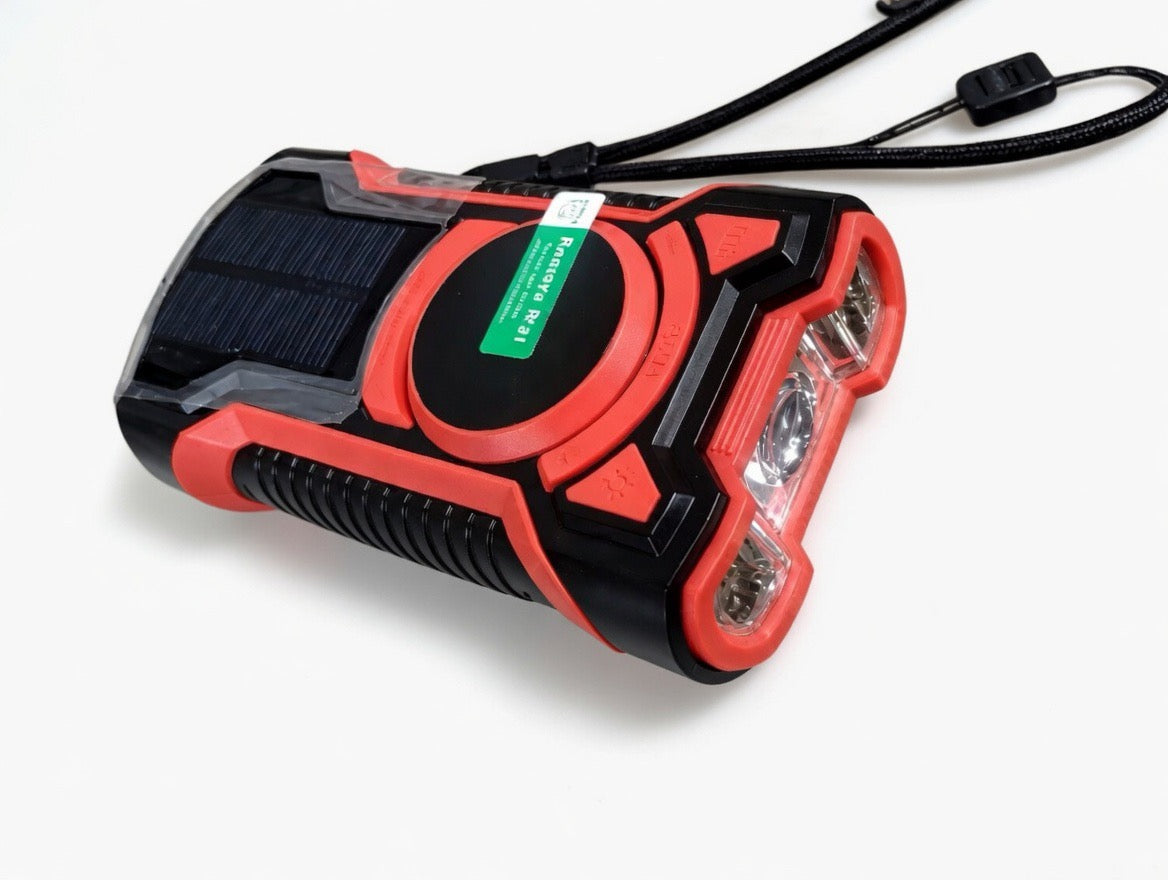 Portable emergency radio with solar panel, flashlight, black and red design on white background